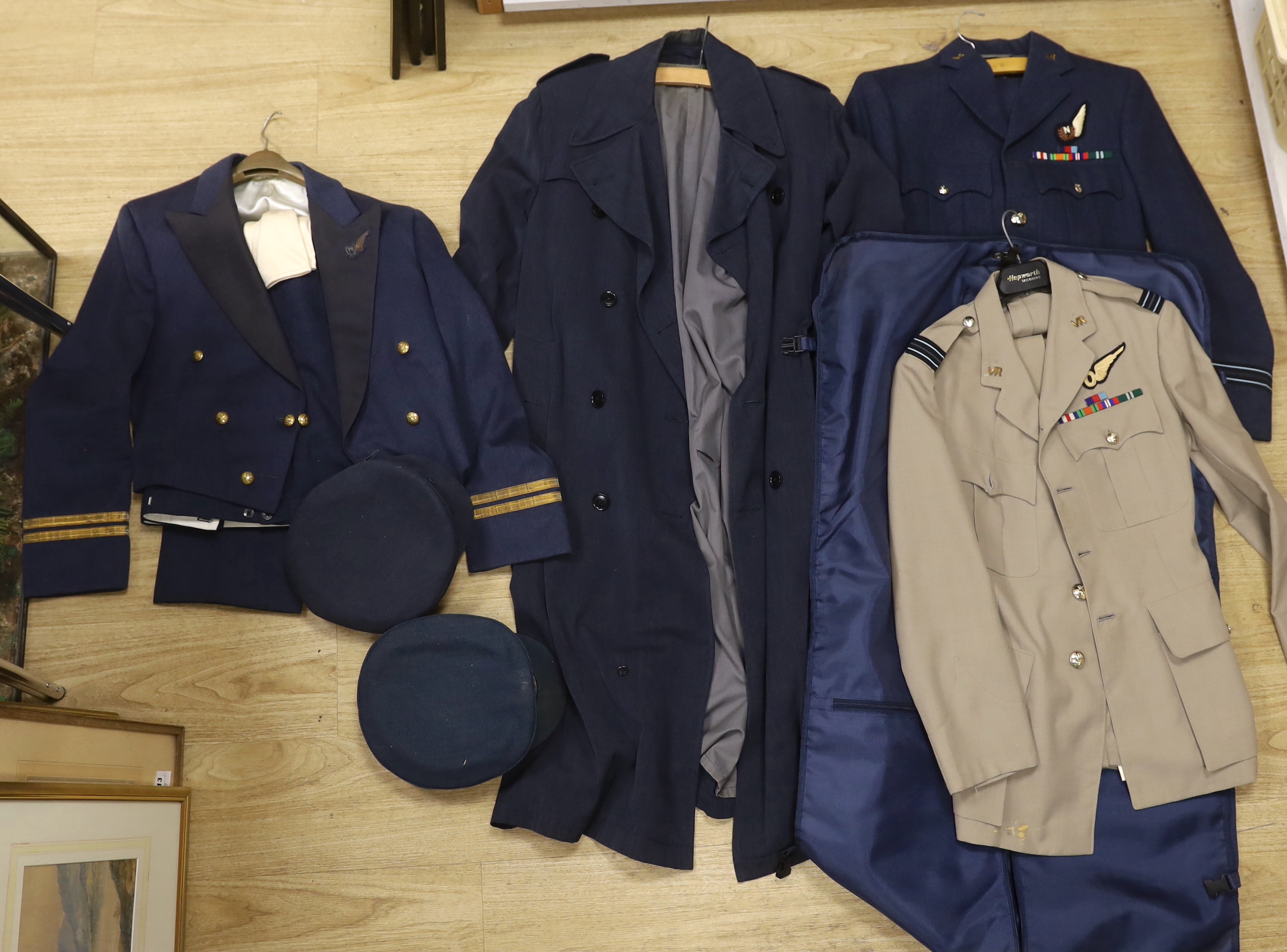 A collection of post-war RAF uniforms, comprising; two caps, double-breasted overcoat, dress uniform of jacket, trousers and gloves, two sets of jacket and trousers with ribbons for WWII awards, plus a pair of navigator’